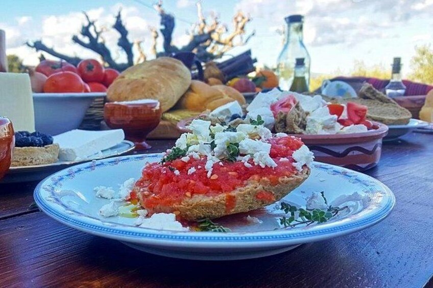 A plate with a food item topped with red and white toppings, surrounded by various other food items and a bottle in the background. 1