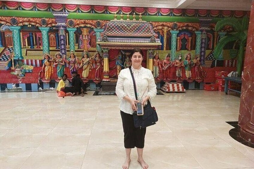 A person standing in front of a colorful temple mural with intricate designs and figures. 2