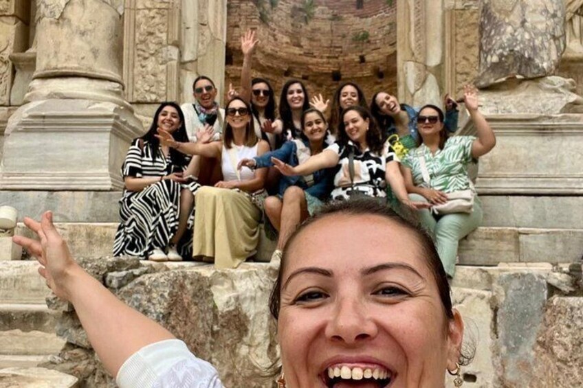 A group of people sitting on stone steps in front of a historical building with columns. 3