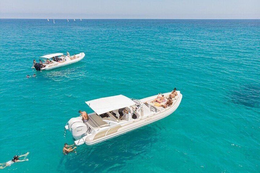 A white motorboat with people on board and another smaller boat nearby in turquoise waters. 4