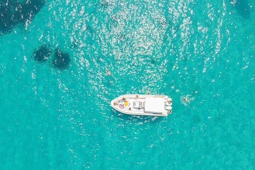 An aerial view of a boat on turquoise water with two small islands in the background. 5