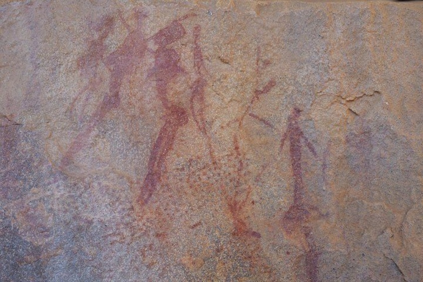 Superficie rocosa con pinturas antiguas en rojo de figuras humanas. 5