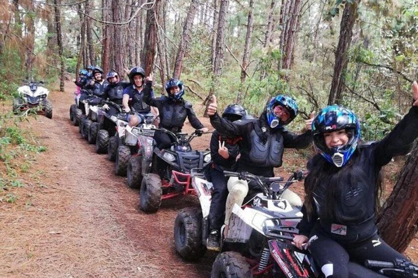 Un groupe de personnes conduisant des quads dans une zone boisée. 2