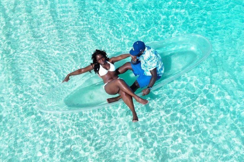 Une personne assise sur un anneau gonflable transparent, dans une piscine à l’eau d’un bleu limpide. 5