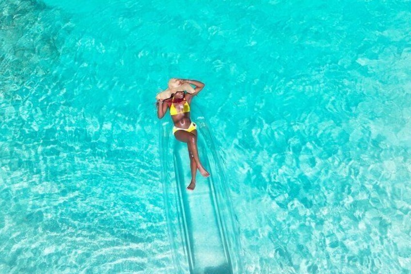 Une personne allongée sur un tube transparent dans une piscine à l’eau d’un bleu limpide. 4