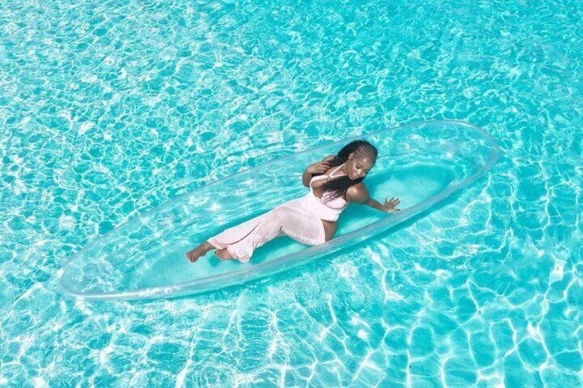 Une personne flotte sur un grand flotteur gonflable transparent dans une piscine à l’eau bleue. 1