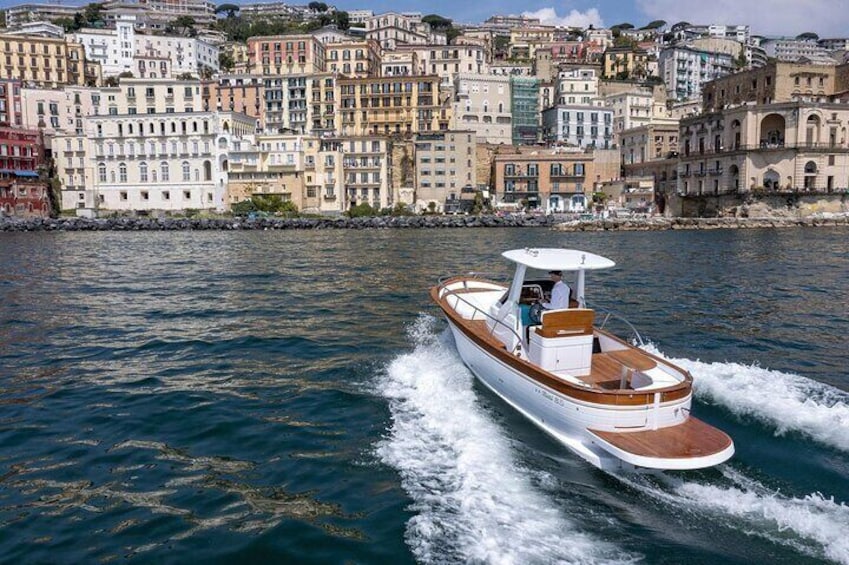 A speedboat moving through a body of water with a cityscape in the background. 4