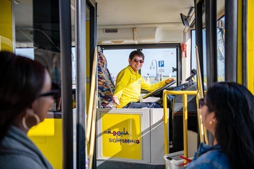 A bus interior with a driver wearing a yellow jacket, a passenger window, and a door. 4