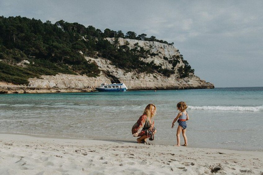 Une plage avec un bateau en arrière-plan et une falaise rocheuse. 2