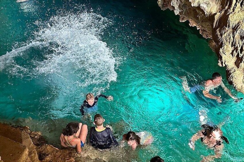 A group of people swimming in a clear blue pool with rocky formations around. 4