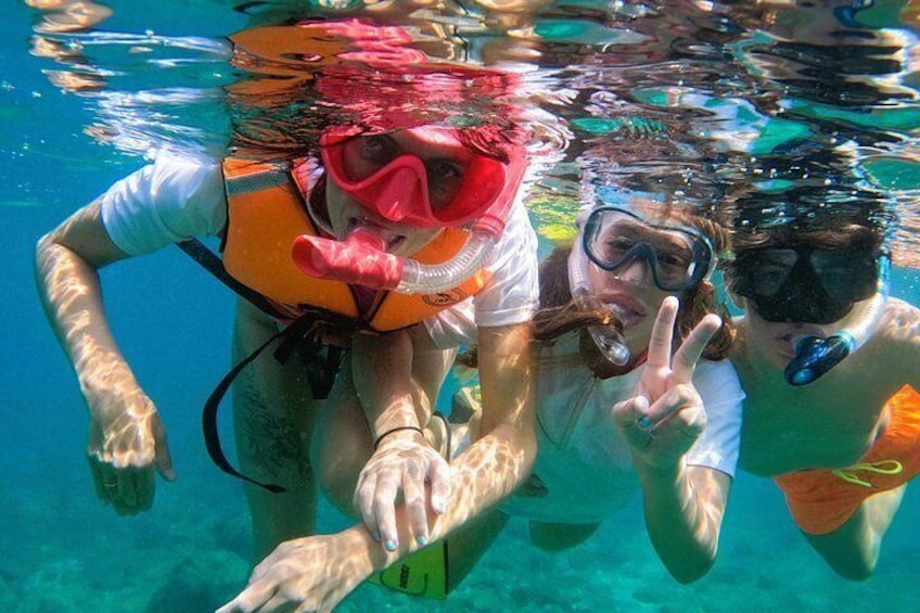 Tre personer som snorklar under vattnet, iförda flytvästar och snorkelmasker. 5