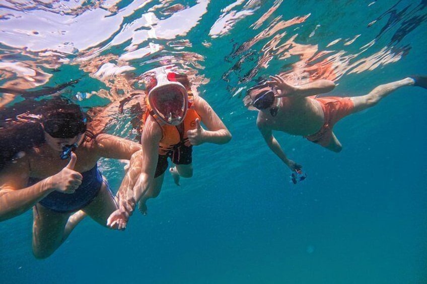 Tre personer som snorklar under vattnet. 4