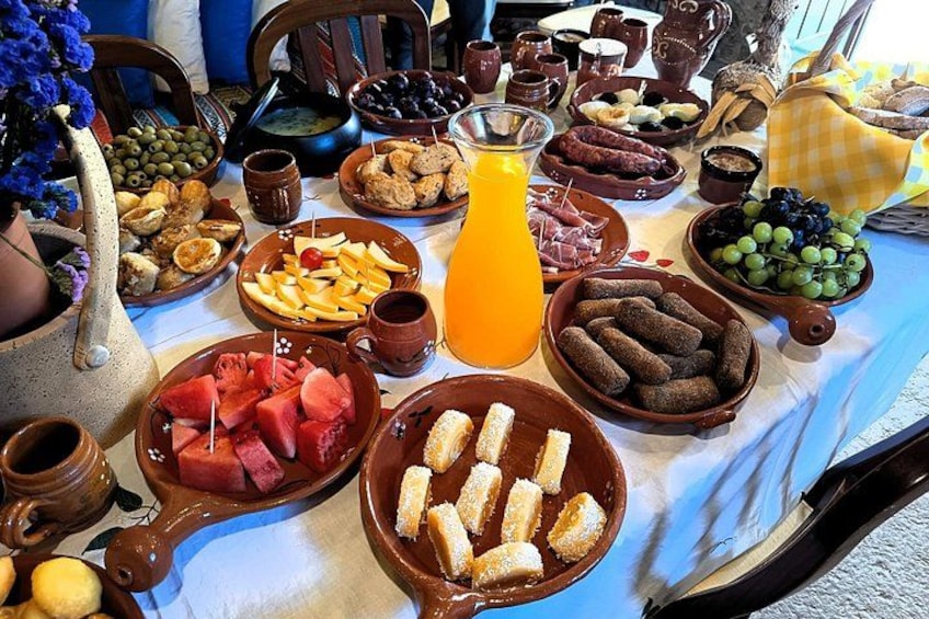 Una mesa con diferentes alimentos, entre ellos frutas, pan y una jarra de jugo de naranja. 3