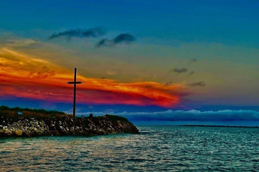 A cross on a rocky outcrop by the sea during sunset. 2