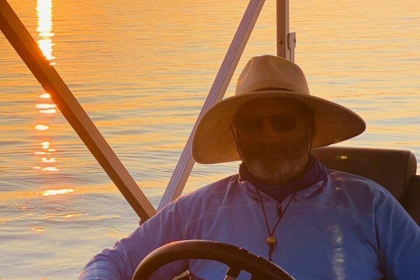 A person in a boat steering, with a sunset in the background. 4