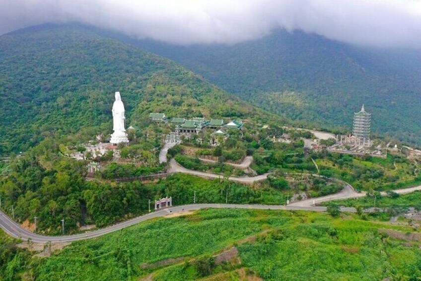 A white statue on a hill, a pagoda, and winding roads in a mountainous area. 5