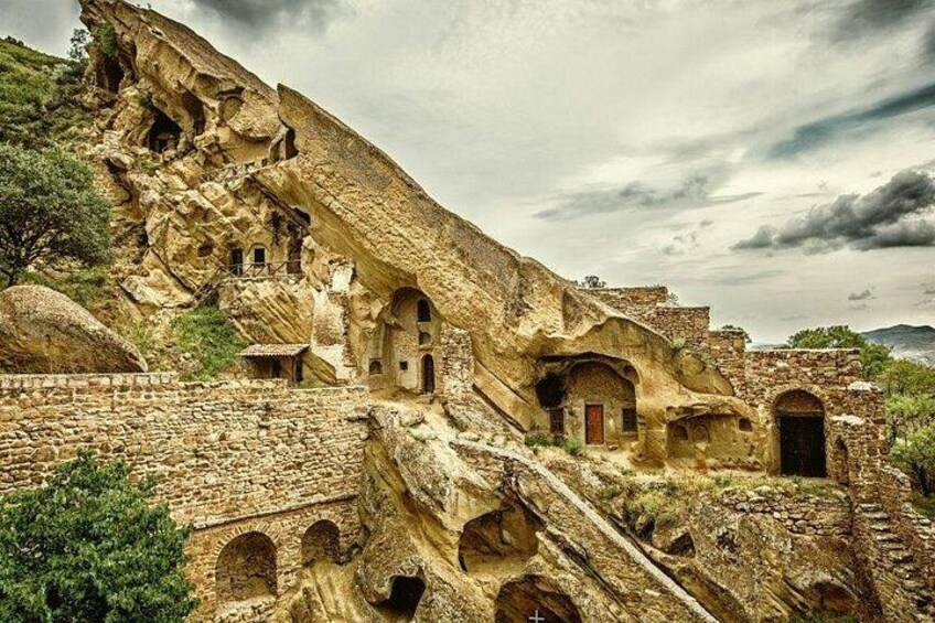 Architettura scavata nella roccia, con diverse strutture simili a grotte e una scala. 3