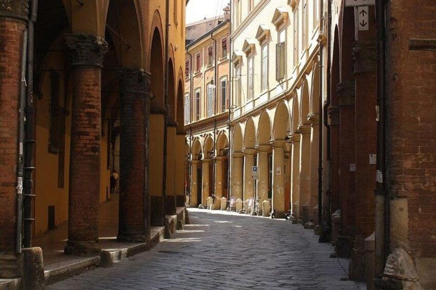 Une rue pavée bordée de bâtiments historiques, caractérisés par leurs fenêtres en arc et leurs façades en briques. 5