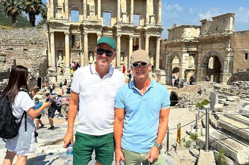 Two people standing in front of ancient ruins with columns and arches. 2