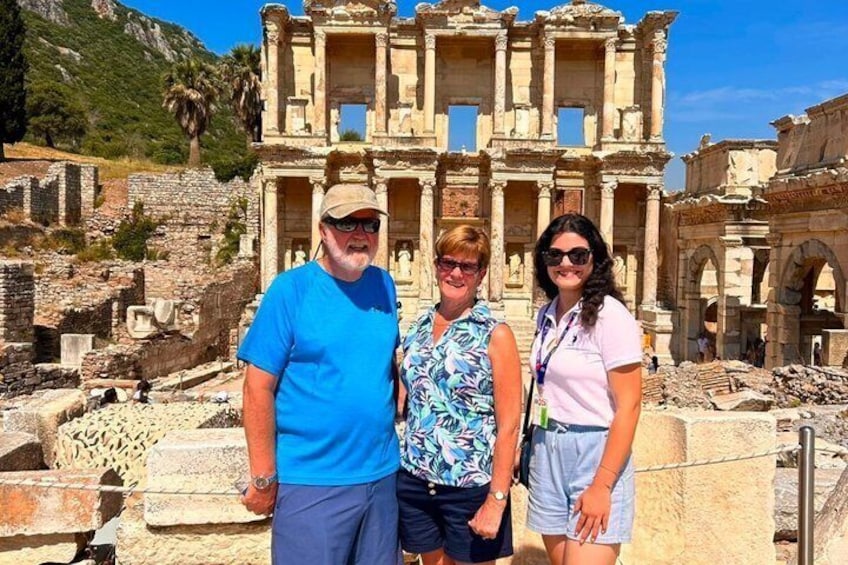 Three people standing in front of an ancient ruin with columns and arches. 2