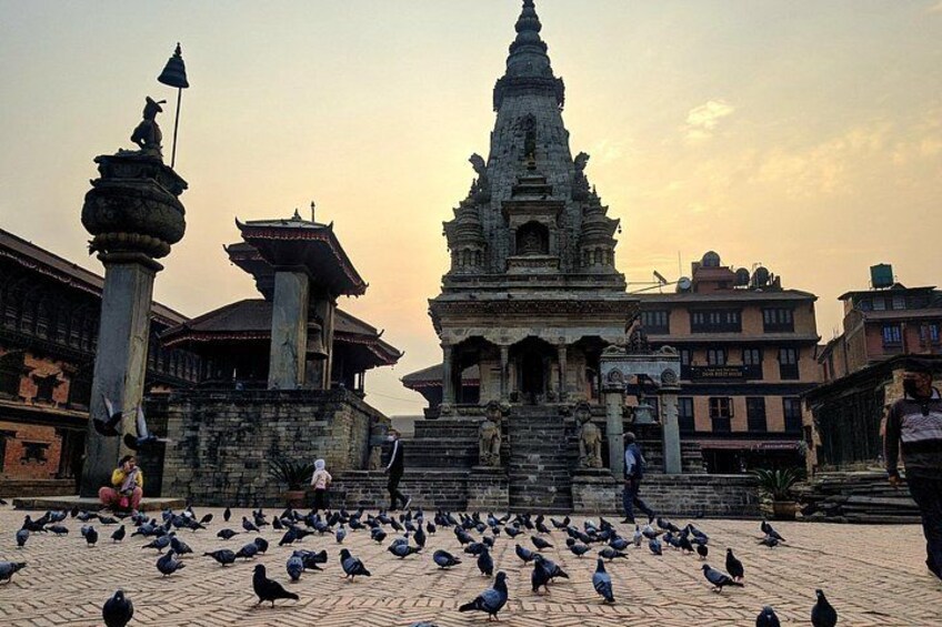 A temple with intricate architecture, a large gathering of pigeons, and a few people in the foreground. 3