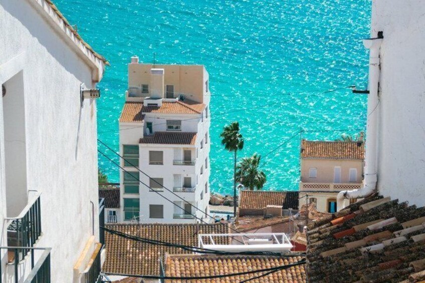 A coastal town with buildings, a boat, and a clear blue sea. 2