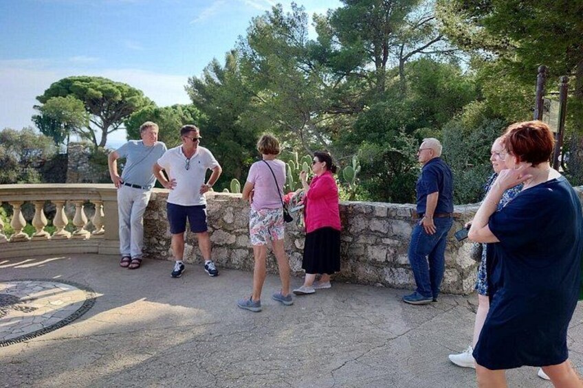 A group of people standing on a stone wall overlooking a landscape with trees and a clear sky. 4