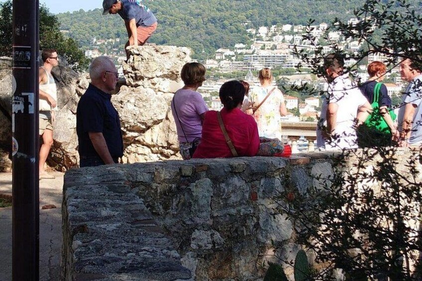 A group of people at a rocky overlook with a view of a town in the background. 3