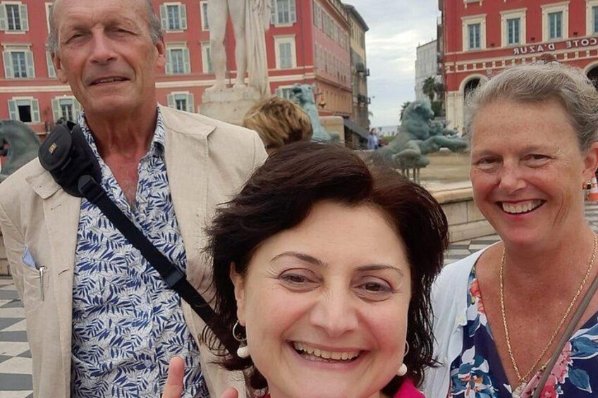 A group of people in an outdoor setting with buildings and a statue in the background. 5