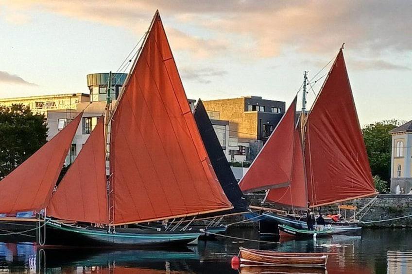 A row of sailboats with red sails docked at a marina. 5