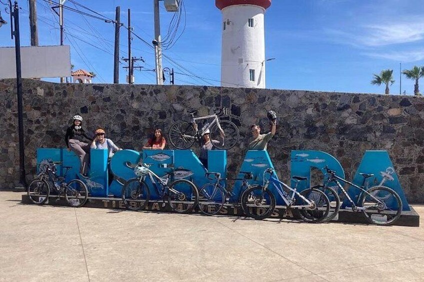 Un grupo de personas posando con bicicletas frente a un faro. 5