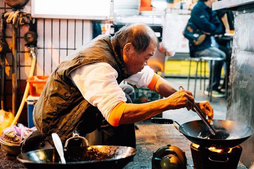 A person cooking with a wok over an open flame. 2