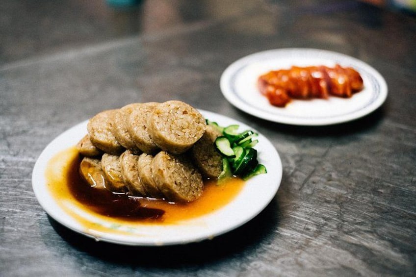 A plate of sliced meat with a sauce and a side of red sauce. 3