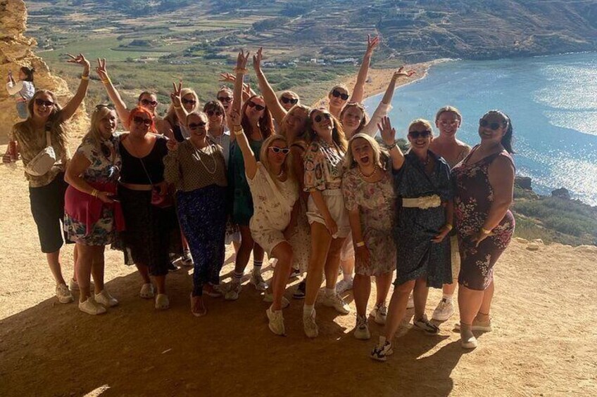 Un grupo de personas de pie en un acantilado con vistas a un paisaje costero. 5