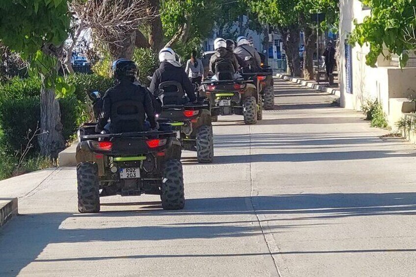 Un grupo de personas circulando en vehículos todo terreno por una calle bordeada de árboles. 4
