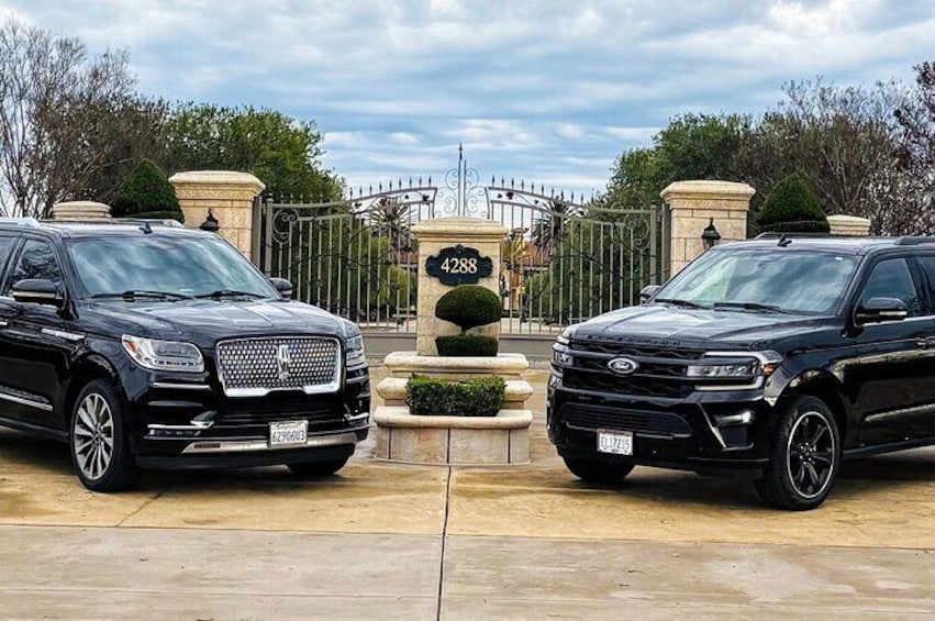 Dos SUVs negros estacionados frente a una entrada con puerta y un letrero que dice '4288'. 2