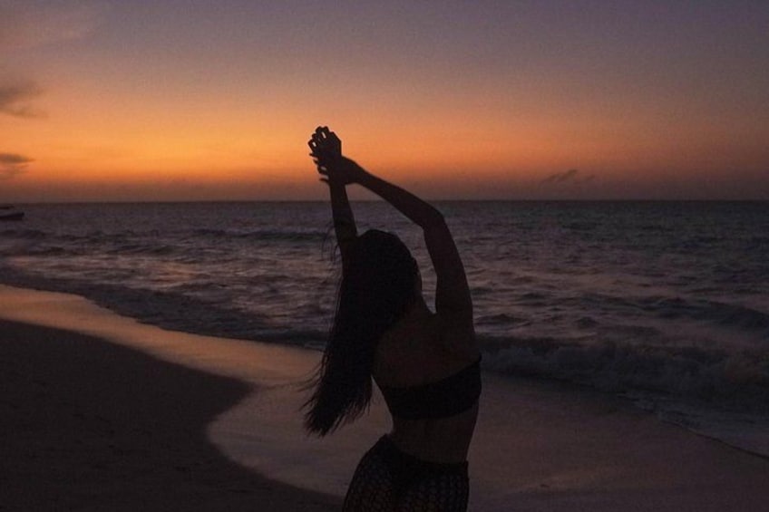 A beach at sunset with waves and a person stretching. 5