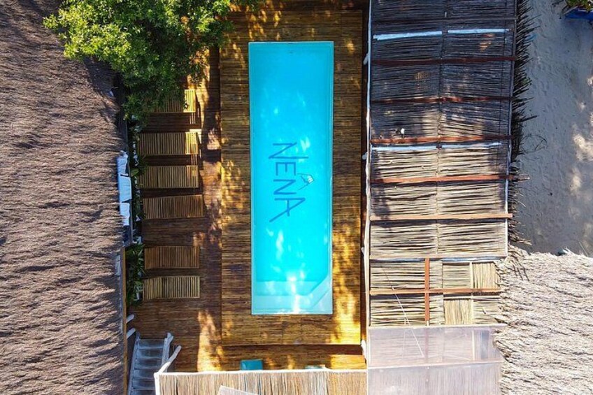 A wooden deck with a pool, surrounded by a wooden fence and a sandy area. 1