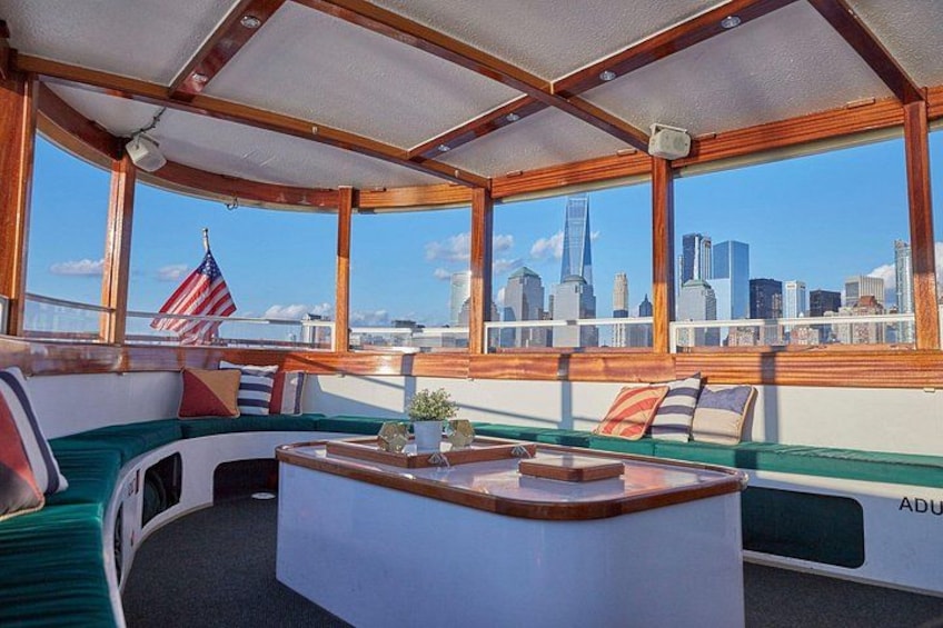 A boat interior with a cityscape view, a wooden ceiling, and a cushioned seating area. 3