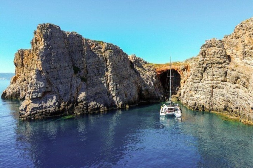 Eine felsige Küstenlinie mit einem Boot, das in der Nähe des Eingangs einer Höhle vor Anker liegt. 2