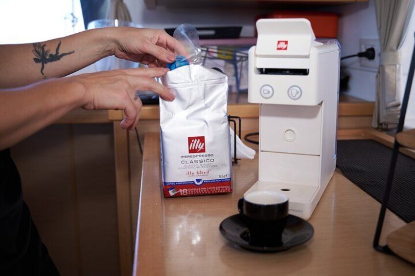 A person handling a coffee bag and a coffee machine on a wooden table. 3