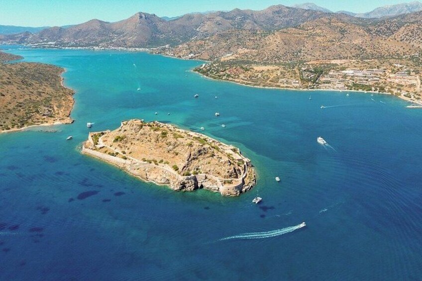 A coastal landscape with a small island, clear blue waters, and distant mountains. 3