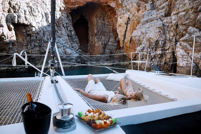 A person lying on a white mat on a boat with a rocky cave in the background. 5