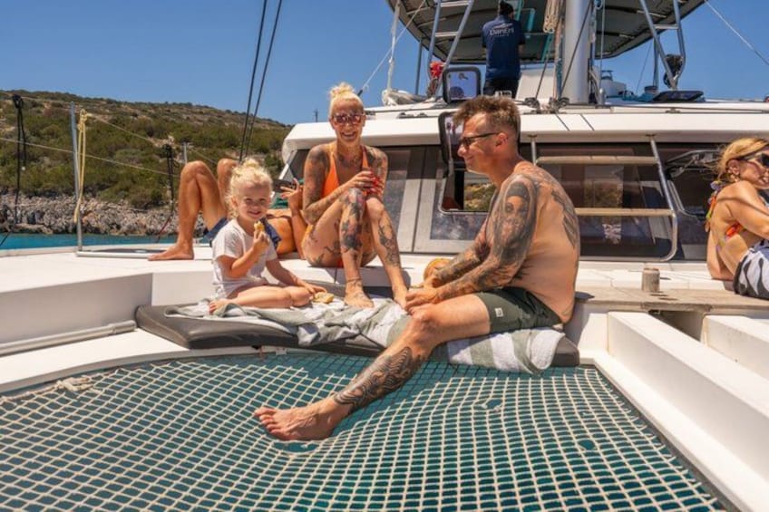 A family on a boat with a child, adults with tattoos, and a clear blue sky. 5