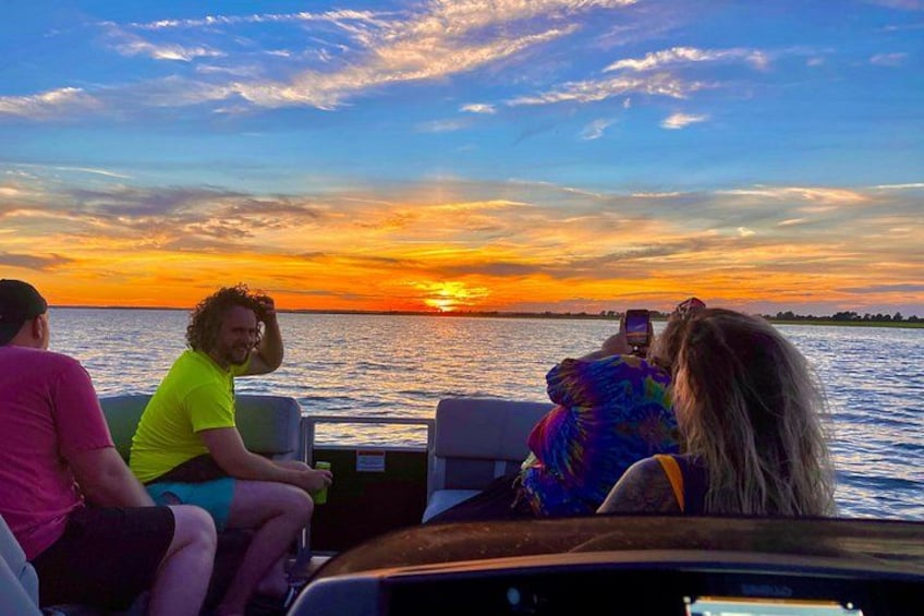A sunset over water with people on a boat. 1