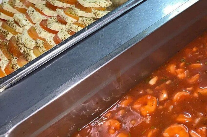 A metal tray with a tomato-based dish and a baked dish with herbs. 2