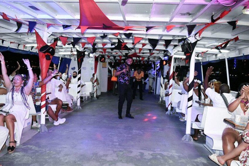 A decorated indoor space with people seated and standing, some raising their hands. 3