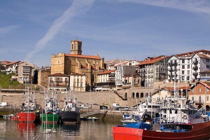 A harbor with boats, a prominent church, and residential buildings. 2