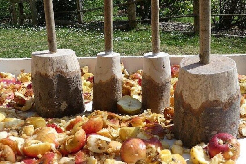 A wooden barrel with a wooden handle, surrounded by apple peels and apple pieces. 4