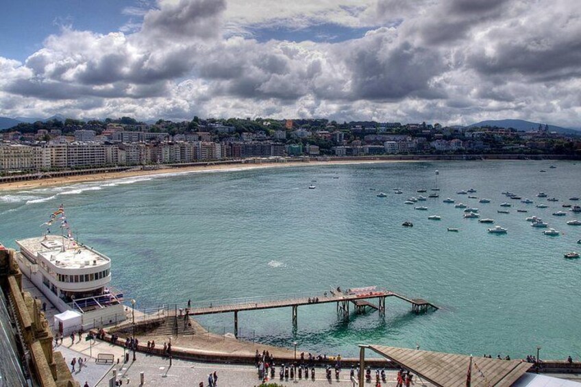 A coastal cityscape with a pier, boats, and a beach. 3